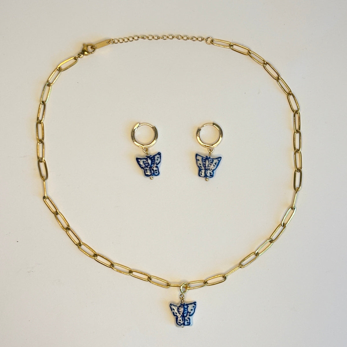 Gold chain necklace with blue butterfly charms on a white background