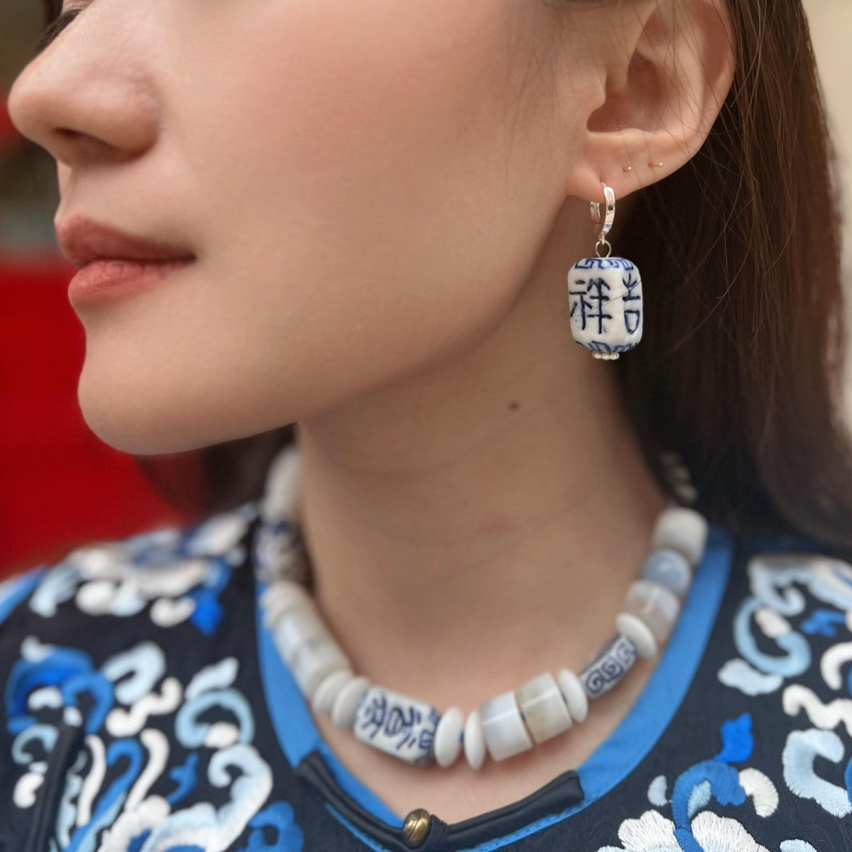 Close-up of a person wearing a necklace and earrings with intricate designs.
