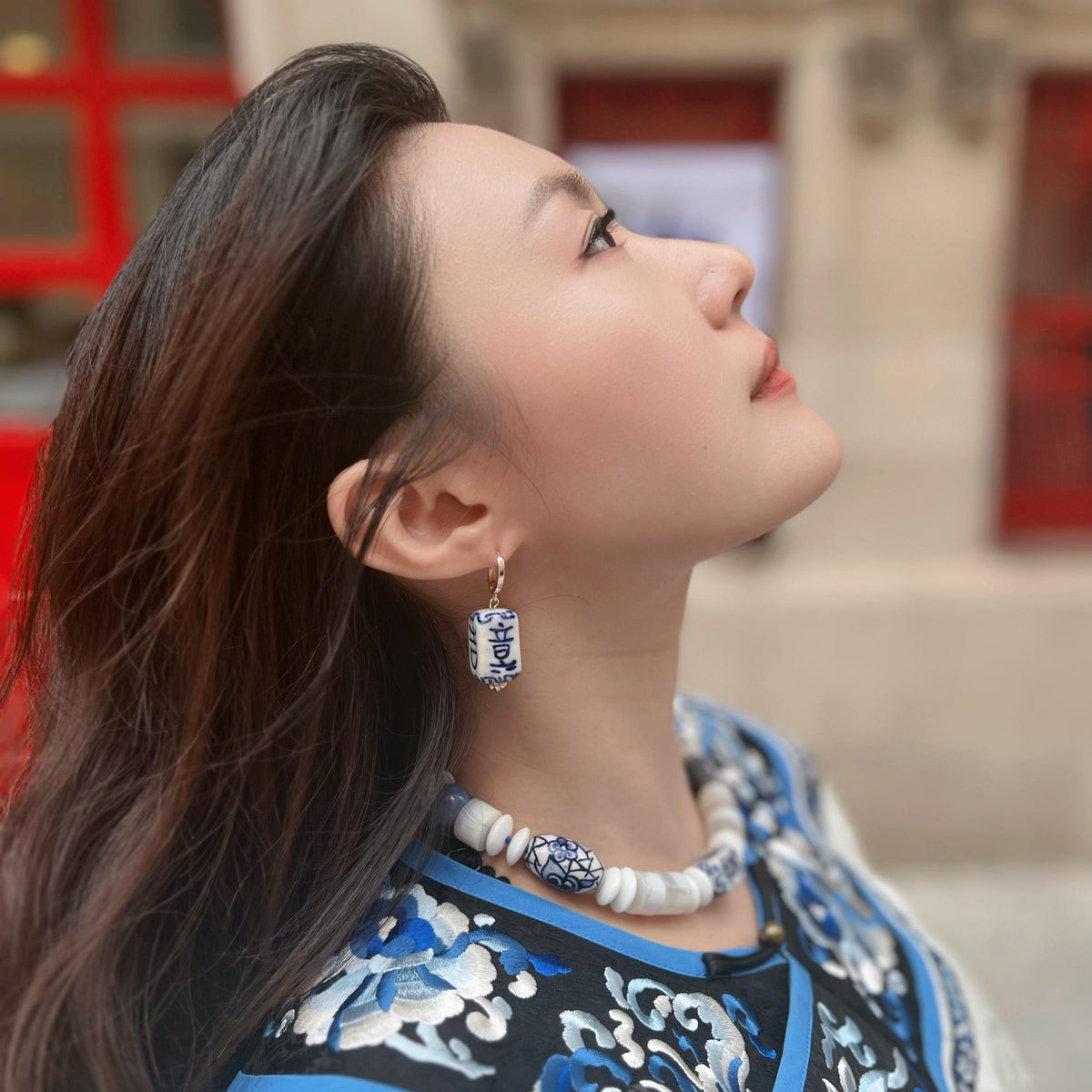 Woman wearing traditional attire with intricate patterns, earrings, and necklace.