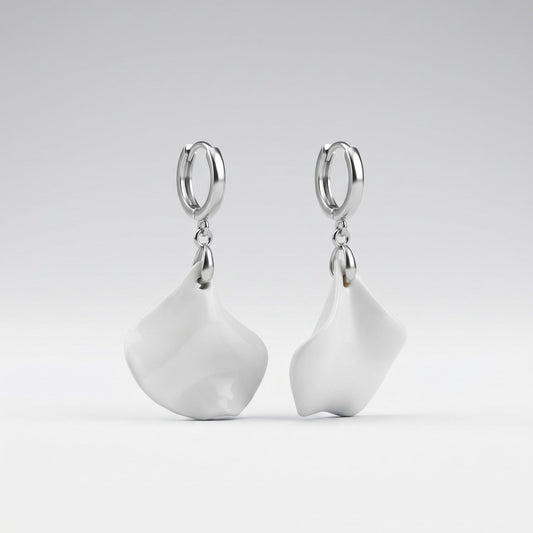 A pair of silver hoop earrings with large, organic-shaped white drop charms, displayed against a clean light gray gradient background.