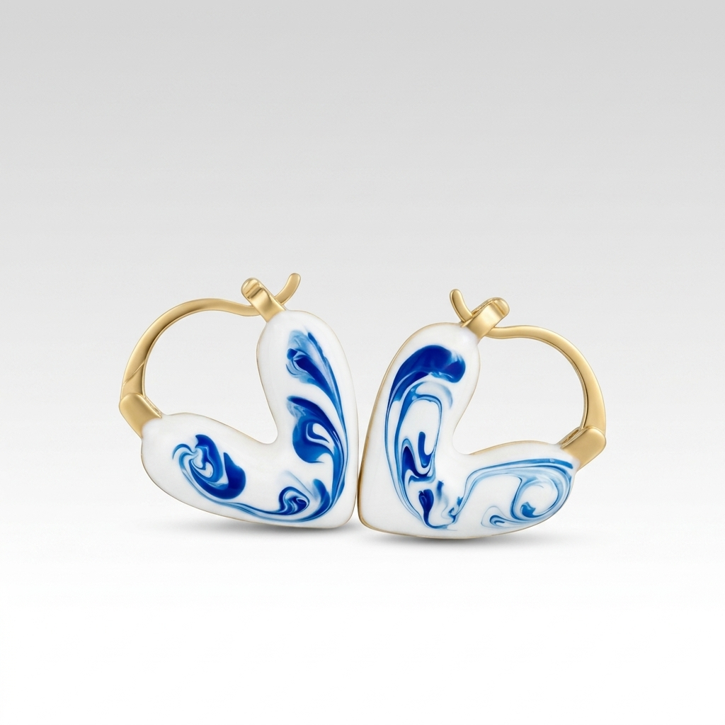 A pair of gold hoop earrings with white enamel inserts featuring blue marbled swirl patterns, shown against a light gray gradient background.