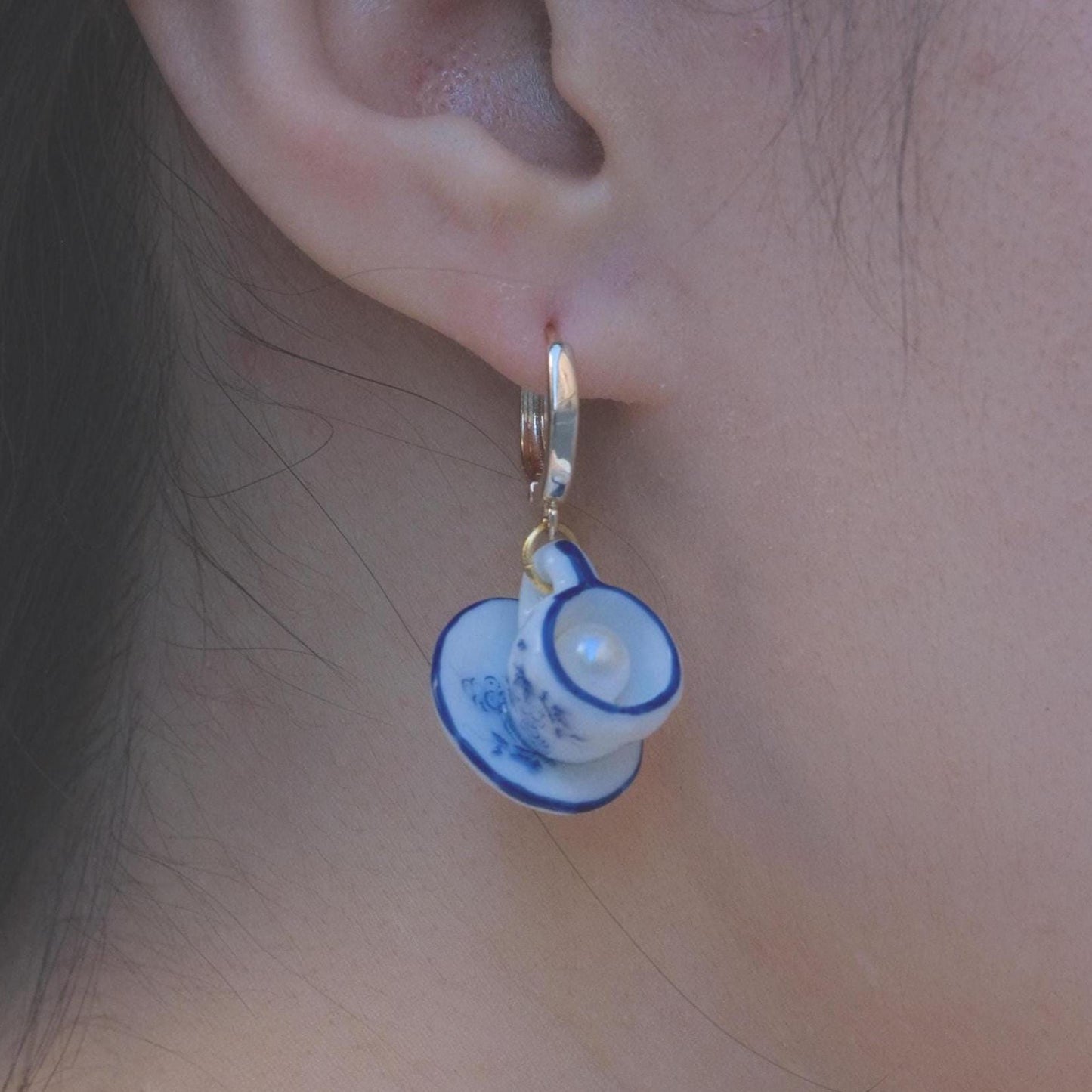 Close-up of an ear wearing a unique earring with a small cup design.