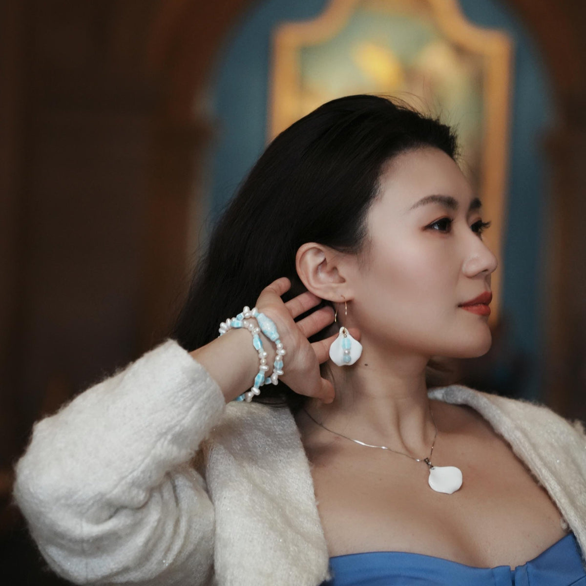 Woman wearing earrings and a necklace with a blurred background
