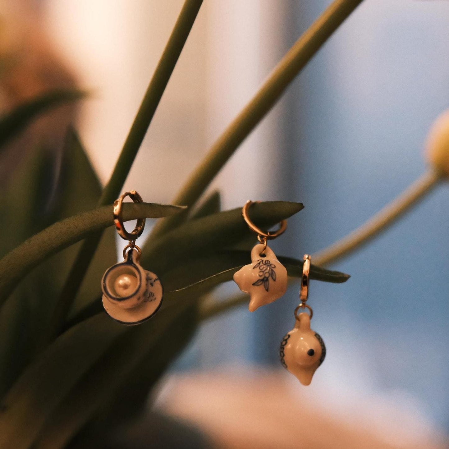 Three unique earrings hanging on a plant with a blurred background