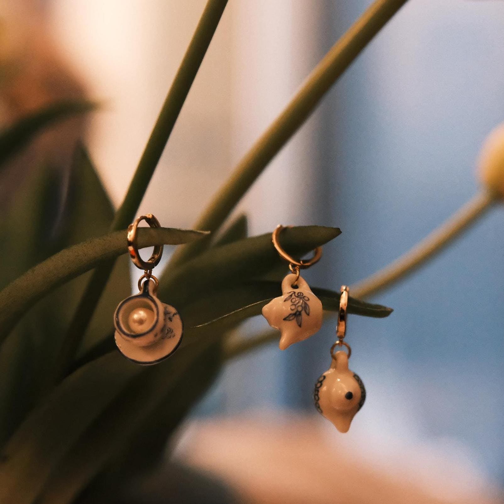 Three unique earrings hanging on a plant with a blurred background